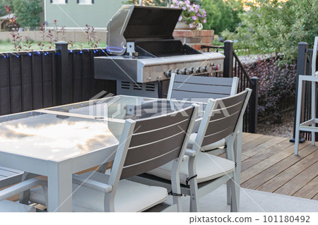 Morning on a summer day. Fully furnished backyard patio with a grill, sitting area, and umbrella. 101180492