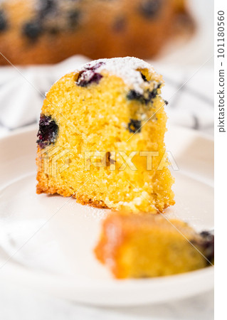 Slicing freshly baked lemon blueberry bundt cake with powdered sugar dusting. Slicing freshly baked lemon blueberry bundt cake with powdered sugar dusting. 101180560
