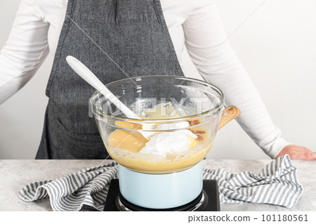 Melting chocolate chips and other ingredients in a glass mixing bowl over boiling water to prepare eggnog fudge. Melting chocolate chips and other ingredients in a glass mixing bowl over boiling water to prepare eggnog fudge. 101180561
