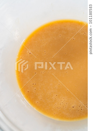 Mixing ingredients with a hand mixer in a small mixing bowl to make the eggnog caramel sauce. 101180583