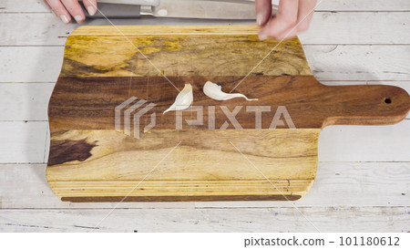 Mincing organic garlic on a wood cutting board. 101180612