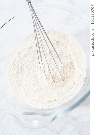 Mixing ingredients in a glass mixing bowl to prepare coconut banana pancakes. Mixing ingredients in a glass mixing bowl to prepare coconut banana pancakes. 101180707