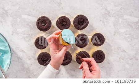Flat lay. Step by step. Scooping blue buttercream frosting on top of the chocolate cupcakes. Flat lay. Step by step. Scooping blue buttercream frosting on top of the chocolate cupcakes. 101180739