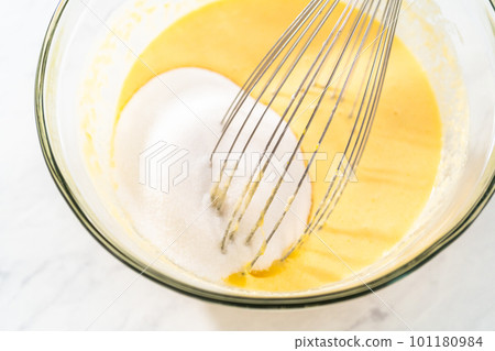 Mixing wet ingredients in a large glass mixing bowl to bake lemon blueberry bundt cake. 101180984