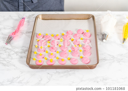 Piping meringue from the piping bags with the metal tip into parchment paper to bake meringue cookies. 101181068