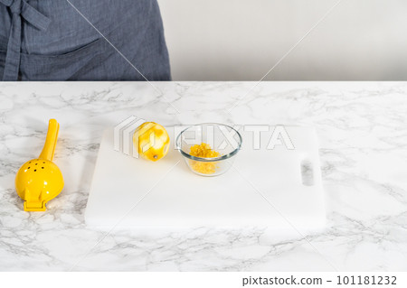 Zesting and juicing fresh lemon on a white cutting board. 101181232