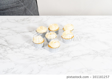 Flat lay. Piping lemon buttercream frosting on top of lemon cupcakes. Flat lay. Piping lemon buttercream frosting on top of lemon cupcakes. 101181257