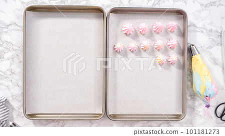 Step by step. Flat lay. Piping unicorn meringue cookies to the baking sheet lined with a parchment paper. 101181273