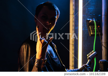 Rebel rockstar woman playing at electric guitar in studio preparing music for rock concert, testing instrument sound. Guitarist performer with grunge jacket performing metal song working at punk album Rebel rockstar woman playing at electric guitar in studio preparing music for rock concert, testing instrument sound. Guitarist performer with grunge jacket performing metal song working at punk album 101182109