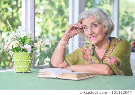 Beautiful elderly woman reads a book at the country house 101182644