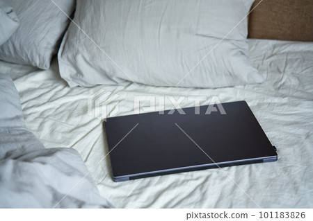 Opened laptop in unmade bed with pillows and crumpled bedsheets at morning. Comfortable workplace for freelancer, work from home Opened laptop in unmade bed with pillows and crumpled bedsheets at morning. Comfortable workplace for freelancer, work from home 101183826