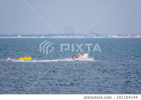 Tubers on their donuts being towed behind a power boat on a dam for recreational fun Tubers on their donuts being towed behind a power boat on a dam for recreational fun 101184144