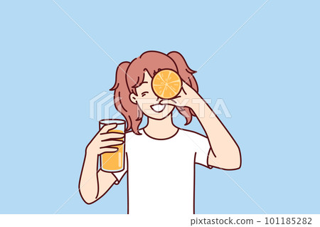 Little girl with glass of orange juice in hands smiling holding half of citrus fruit near face 101185282