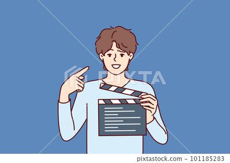 Man producer with clapboard in hands looks at screen while working on set of film or clip 101185283