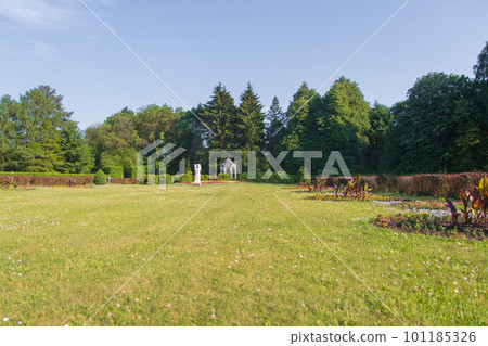 a large green trimmed lawn in a park with statues and a gazebo, with trees and shrubs around a large green trimmed lawn in a park with statues and a gazebo, with trees and shrubs around 101185326