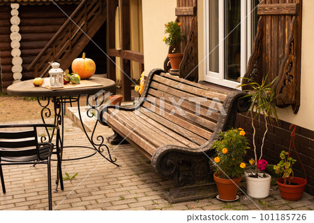 autumn, a wooden bench and a table near the house, on the table are orange pumpkin and apples autumn, a wooden bench and a table near the house, on the table are orange pumpkin and apples 101185726