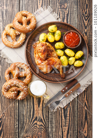 Bavarian roast chicken Hendl with boiled potatoes served with beer and pretzel closeup. Vertical top view 101189026