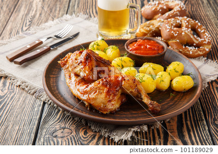 Grilled half chicken with boiled potatoes and tomato sauce served with beer and pretzel closeup. Horizontal 101189029