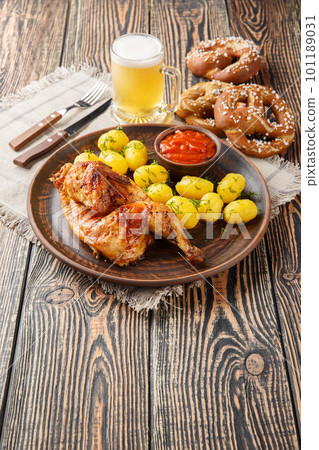 Bavarian roast chicken Hendl with boiled potatoes served with beer and pretzel closeup. Vertical Bavarian roast chicken Hendl with boiled potatoes served with beer and pretzel closeup. Vertical 101189031