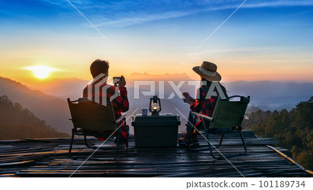 Romantic couple camping outdoors and taking photos with camera while camping at sunrise. Doi Luang Chiang Dao mountains in Chiang Mai. Romantic couple camping outdoors and taking photos with camera while camping at sunrise. Doi Luang Chiang Dao mountains in Chiang Mai. 101189734