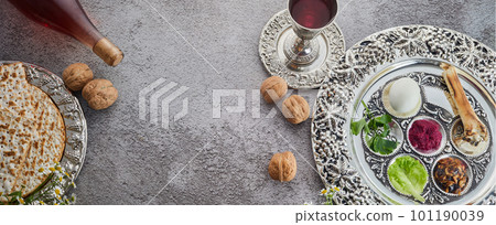 Passover Seder plate with traditional food, walnuts, matza and wine on grunge background 101190039