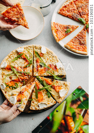 Traditional Italian pizza, vegetables, ingredients on a light background.Top view. a piece of pizza in the hand.Festive table. company of friends 101190851