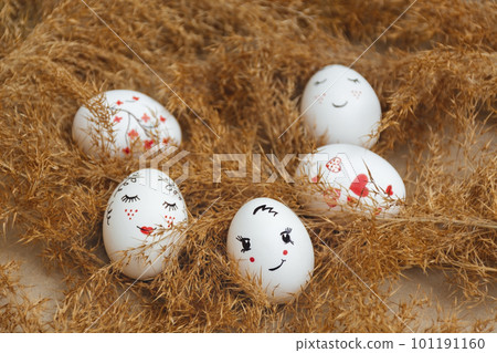 Easter card. Hand made Easter eggs lie in dry natural pampas grass. Painted gentle faces and red hearts. Dry golden reed. Soft selective focus. Happy holidays. Minimalist style. Copy Space 101191160