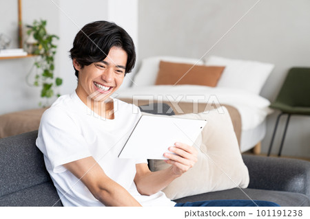 A young man looking at a tablet in the living room A young man looking at a tablet in the living room 101191238