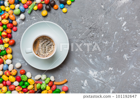 Coffee cup with chocolates and colored candy. Top view on table background with copy space Coffee cup with chocolates and colored candy. Top view on table background with copy space 101192647