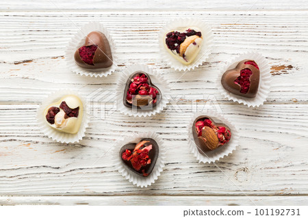 chocolate sweets in the form of a heart with fruits and nuts on a colored background. top view with space for text, holiday concept 101192731