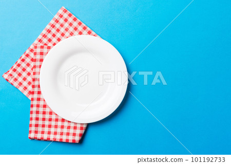 Top view on colored background empty round white plate on tablecloth for food. Empty dish on napkin with space for your design Top view on colored background empty round white plate on tablecloth for food. Empty dish on napkin with space for your design 101192733