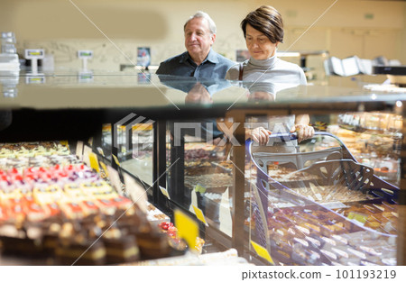 woman chooses cakes at showcase of confectionery department woman chooses cakes at showcase of confectionery department 101193219