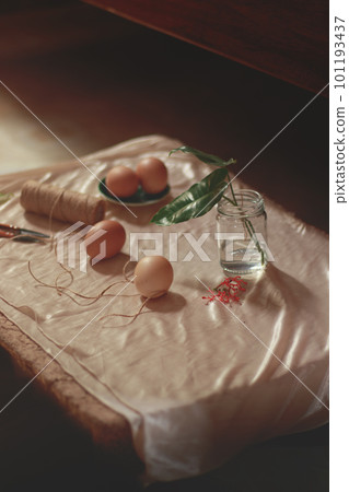Vertical shot of a table with brown eggs, twines and flowers for making handmade rustic easter eggs decor that are zero waste and eco-friendly 101193437