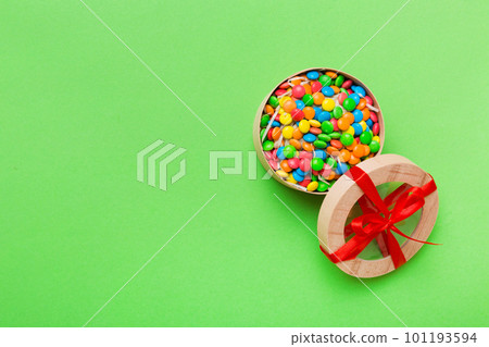 Set of different sweet candy in a paper box with a satin ribbon on a colored background. Holiday concept Set of different sweet candy in a paper box with a satin ribbon on a colored background. Holiday concept 101193594