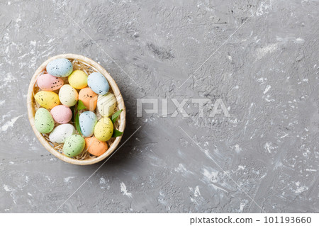 Colorful Easter eggs in wicker basket against colored background, closeup. top view with copy space Colorful Easter eggs in wicker basket against colored background, closeup. top view with copy space 101193660