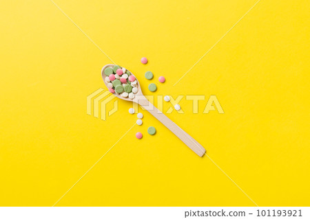 Vitamin capsules in a wooden spoon on a colored background. Pills served as a healthy meal. Drugs, pharmacy, medicine or medical healthycare concept 101193921