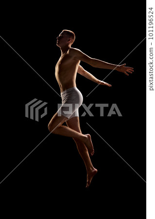 Portrait of young good-looking redhead man wearing underwear and jumping with open hands over dark background 101196524