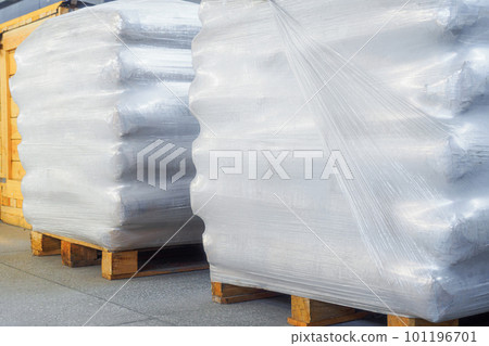 Storage of packaged goods or cargo in warehouse. On wooden pallets there are bags of cement wrapped Storage of packaged goods or cargo in warehouse. On wooden pallets there are bags of cement wrapped 101196701