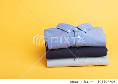 Stack of new color men shirt on wooden desk with yellow space background. Mens fashion clothing concept. 101197706