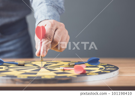 Businessman working in the office and throwing arrow darts in the center of yellow dartboard. Goal and success for business concept. 101198410