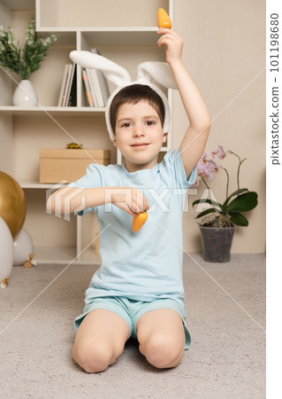 A preschool Easter boy plays with carrots, rabbit ears on his head. A preschool Easter boy plays with carrots, rabbit ears on his head. 101198680