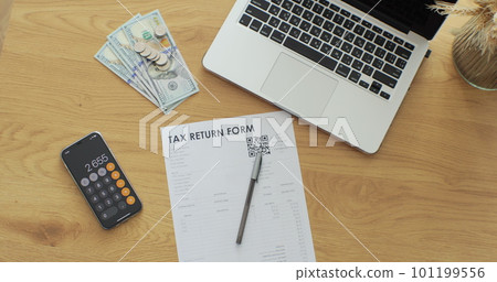 Shot of table with tax return paper forms, laptop and phone with calculator for counting annual budget. 101199556
