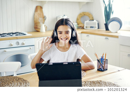 Girl studying online using modern tech at home Girl studying online using modern tech at home 101201324