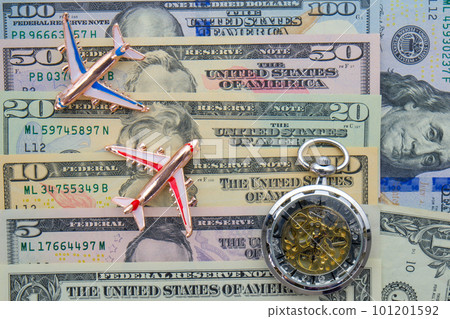 Passenger plane, compass, and pocket watch sitting on US currency bills of different denominations showing concept high cost of flying, time Passenger plane, compass, and pocket watch sitting on US currency bills of different denominations showing concept high cost of flying, time 101201592