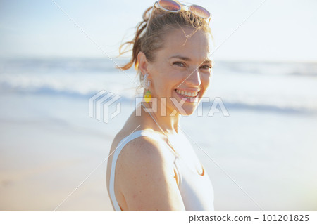 Portrait of smiling stylish woman in white swimwear at beach 101201825