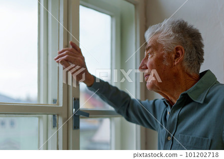 Senior man looking out of window, concept of solitude in retirement. Senior man looking out of window, concept of solitude in retirement. 101202718