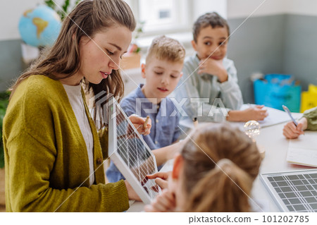 Young teacher with solar panel learning pupils about solar energy. 101202785