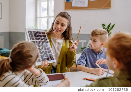 Young teacher with solar panel learning pupils about solar energy. Young teacher with solar panel learning pupils about solar energy. 101202786