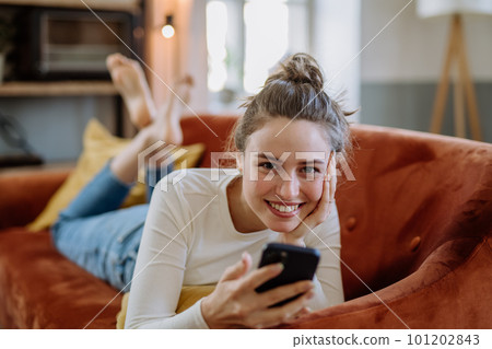 Young woman scrolling her smartphone in the apartment. Young woman scrolling her smartphone in the apartment. 101202843