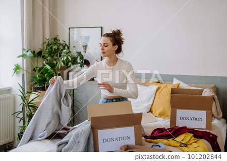 Young woman giving her clothes to charity. Young woman giving her clothes to charity. 101202844